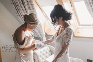 Bridemaids helping bride with buttons on sleeve